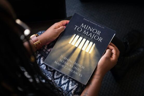 A teenager looks down a copy of Minor to Major the paperback copy. Order yours today.